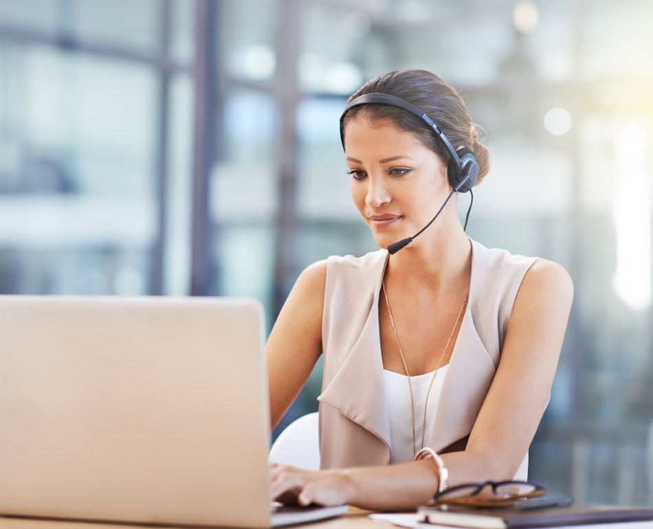 professional sitting with a headset on typing on laptop